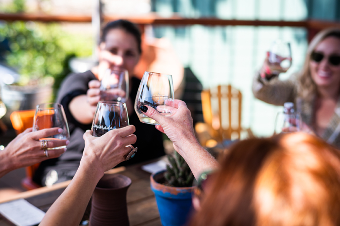 cheers with stemless wine glasses at outdoor wine tasting